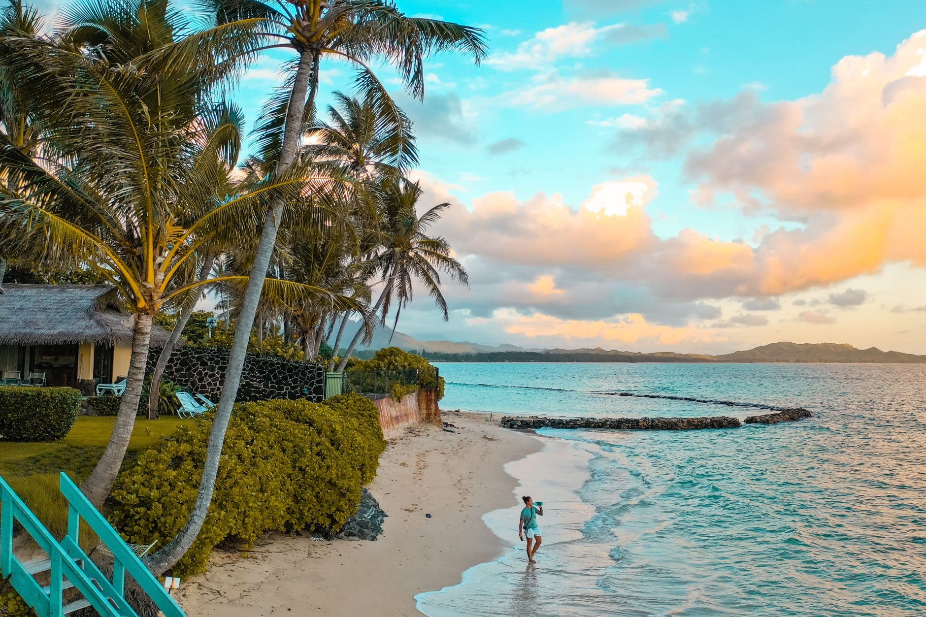 A palm-fringed tropical shoreline at sunset, representative imagery for travel discovery